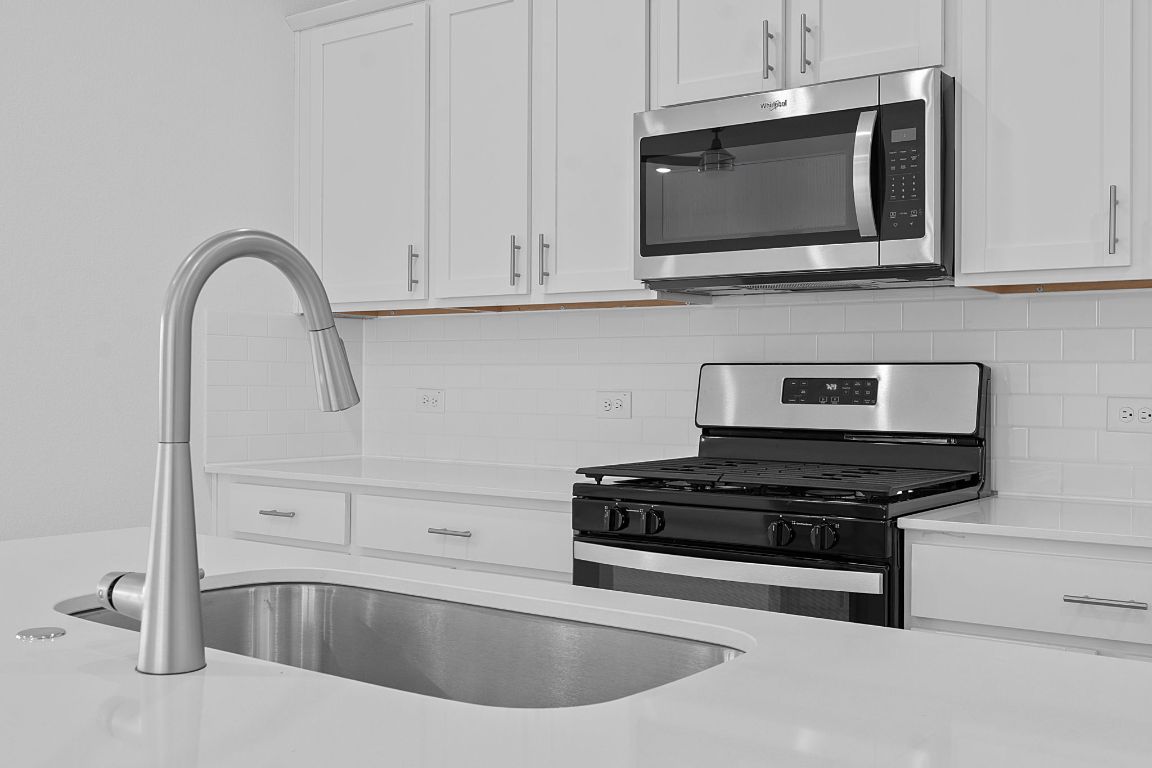 9701 Oxbow Strap Drive Austin, TX 78724 - Photo 19 of 34 Kitchen with appliances with stainless steel finishes, white cabinets, and tasteful backsplash