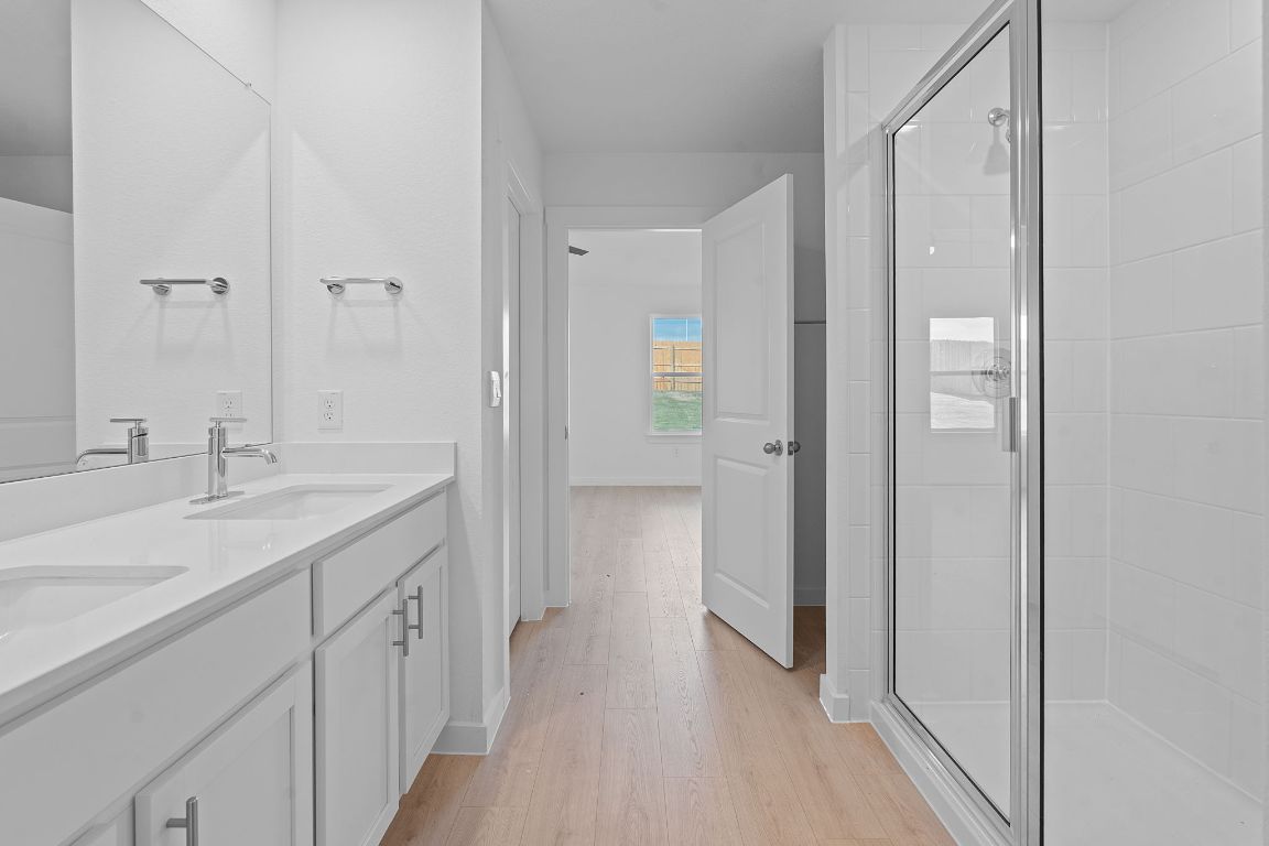 9701 Oxbow Strap Drive Austin, TX 78724 - Photo 24 of 34 Full bath featuring double vanity, light wood-style flooring, and a stall shower