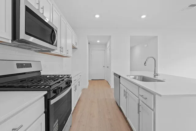 a kitchen with stainless steel appliances a stove sink microwave and cabinets