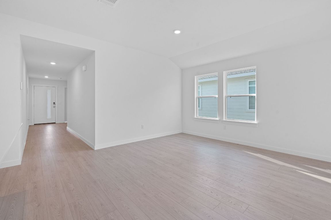 9701 Oxbow Strap Drive Austin, TX 78724 - Photo 9 of 34 Empty room with light wood-style floors, recessed lighting, and lofted ceiling