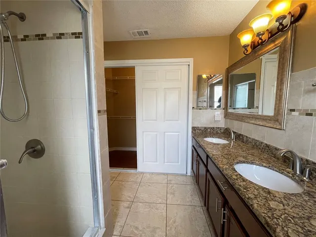 a bathroom with a granite countertop sink a mirror and shower