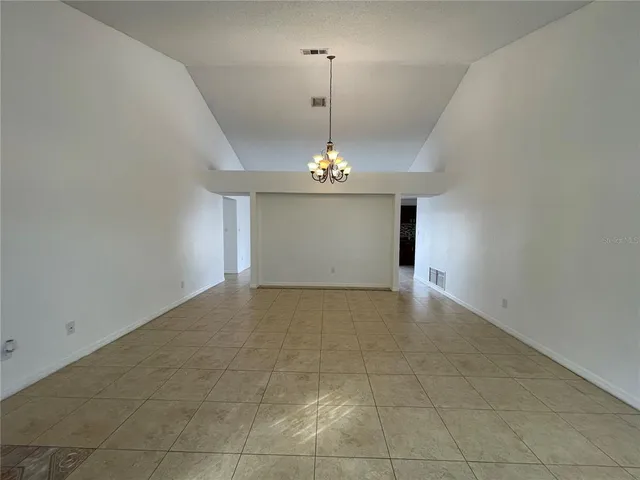 a view of an empty room with a chandelier fan