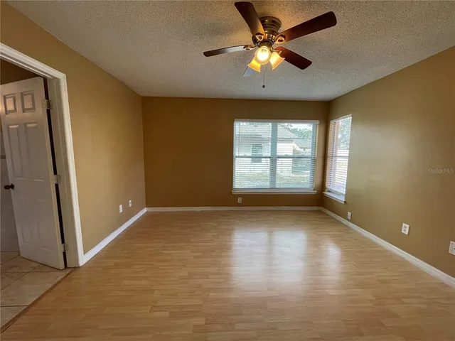 an empty room with windows and fan