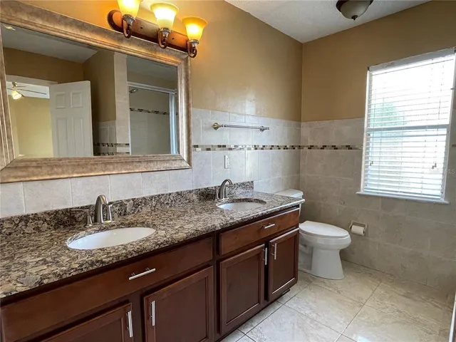 a bathroom with a granite countertop sink toilet and mirror