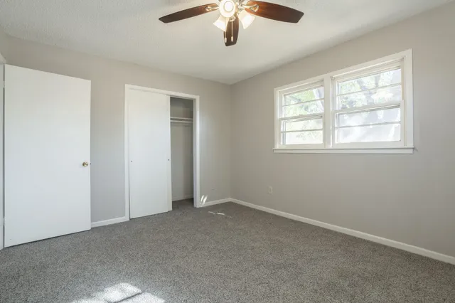 an empty room with windows and chandelier fan