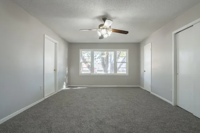 a view of an empty room with a chandelier fan