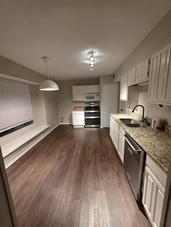 a kitchen with granite countertop a stove and a wooden floors