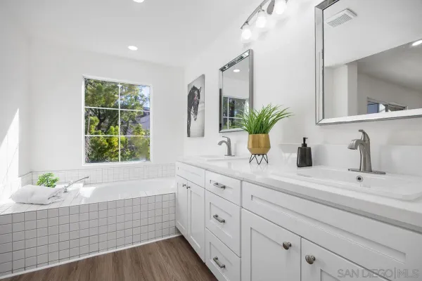 a bathroom with a double vanity sink bathtub and next to a window