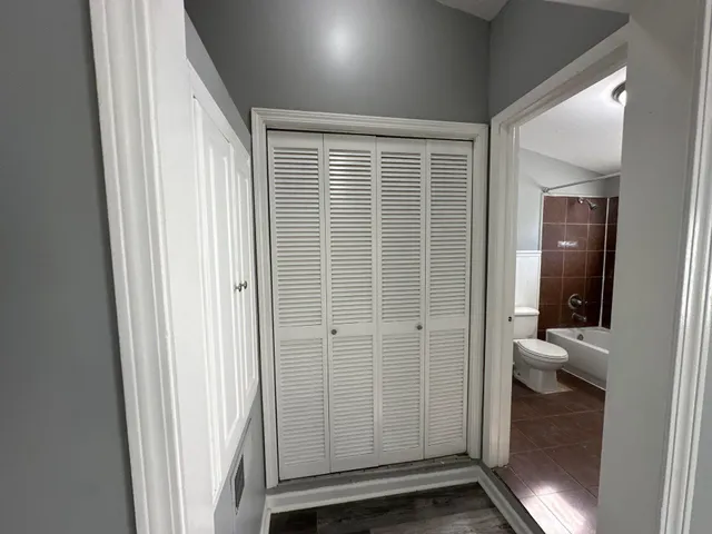 a view of a hallway with wooden floor and a bathroom