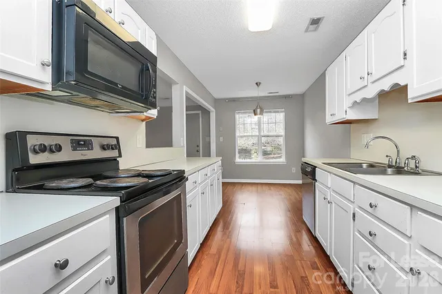 a kitchen with granite countertop a sink a stove and cabinets