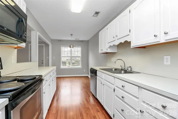 a kitchen with granite countertop a sink a stove cabinets and wooden floor