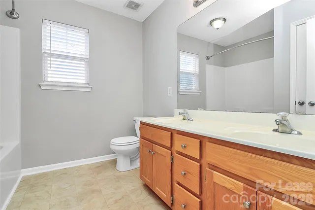 a bathroom with a double vanity sink toilet and a mirror