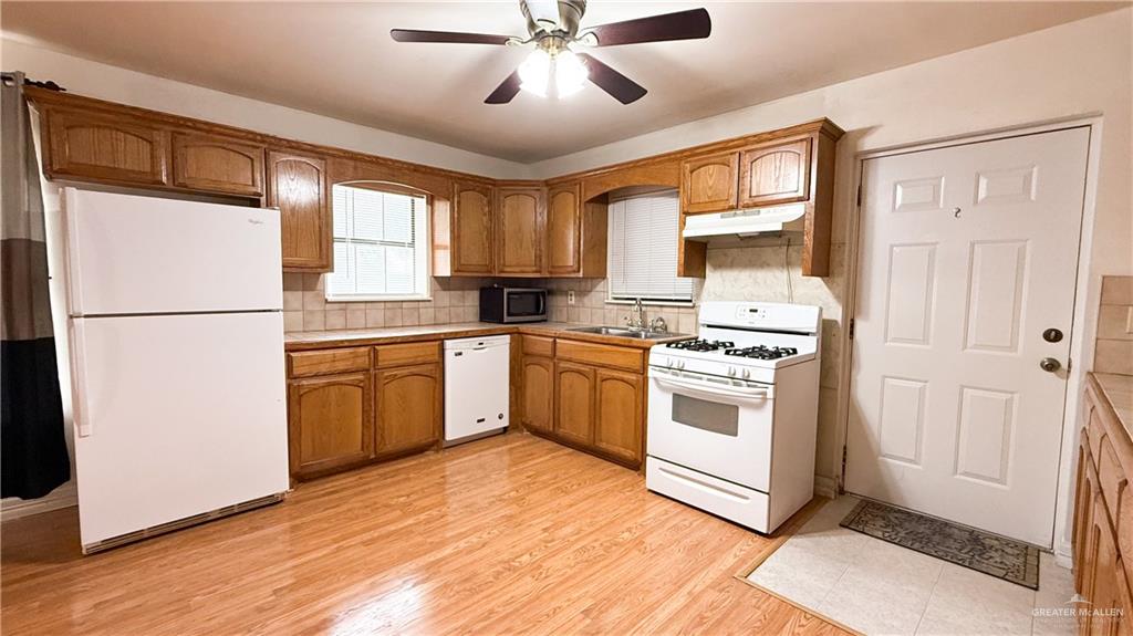 21713 North Western Road Edinburg, TX 78541 - Photo 2 of 24 Kitchen featuring white appliances, ceiling fan, wood finish cabinets, light wood-style flooring, and backsplash