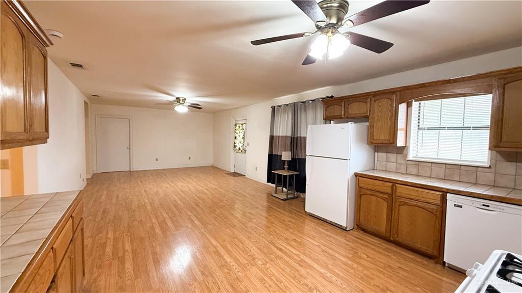 21713 North Western Road Edinburg, TX 78541 - Photo 8 of 24 Kitchen featuring tile counters, ceiling fan, white appliances, light wood finished floors, and wood finish cabinets