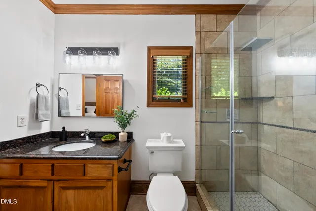 a bathroom with a granite countertop sink toilet and mirror