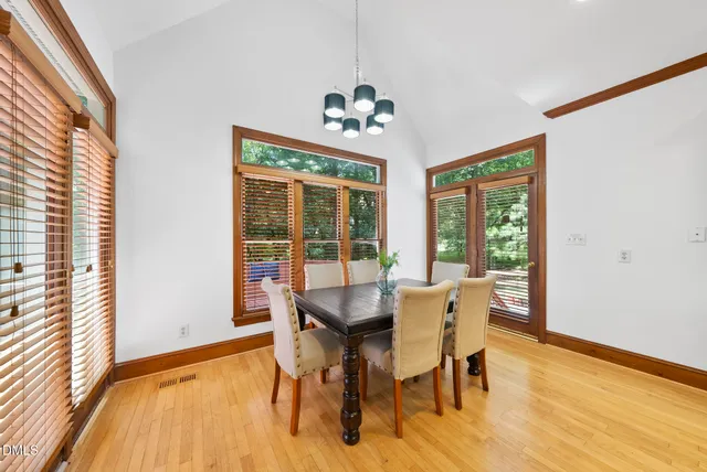 a dining room with wooden floor a chandelier a glass table and chairs