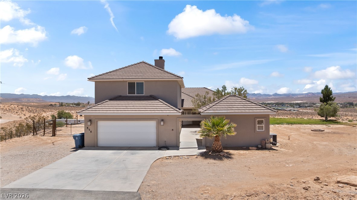575 Gann Avenue Logandale, NV 89021 - Photo 62 of 75 A desert oasis home features a clean driveway, an attached garage, and striking views of the distant mountains.