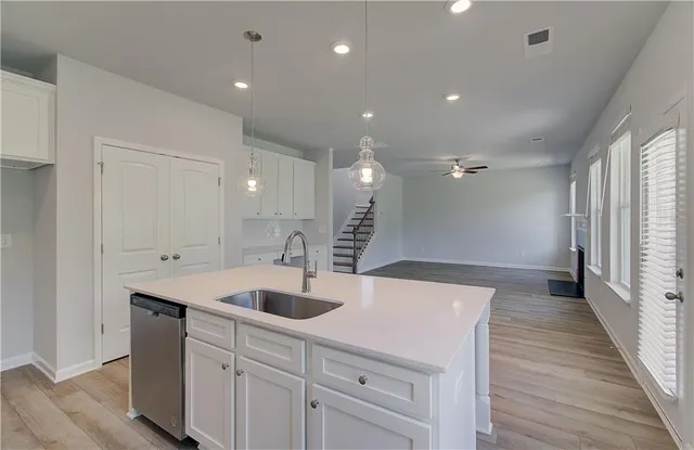 a large white kitchen with a sink and wooden floor