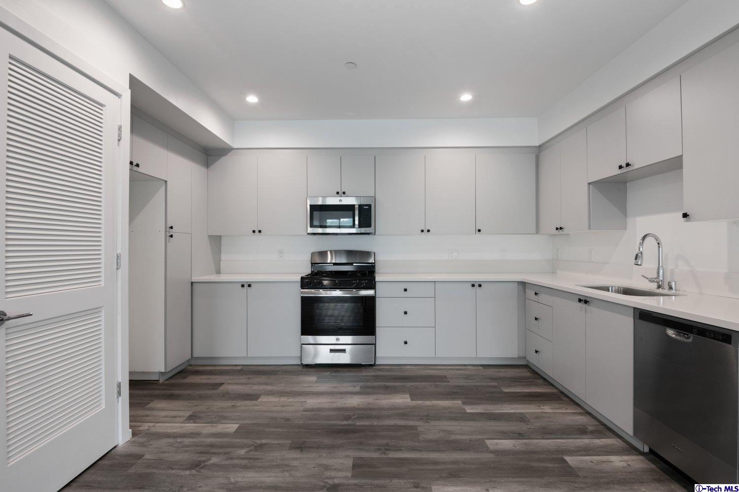 7064 Greeley Street, Unit 202 Tujunga, CA 91042 - Photo 24 of 45 a kitchen with granite countertop white cabinets and stainless steel appliances