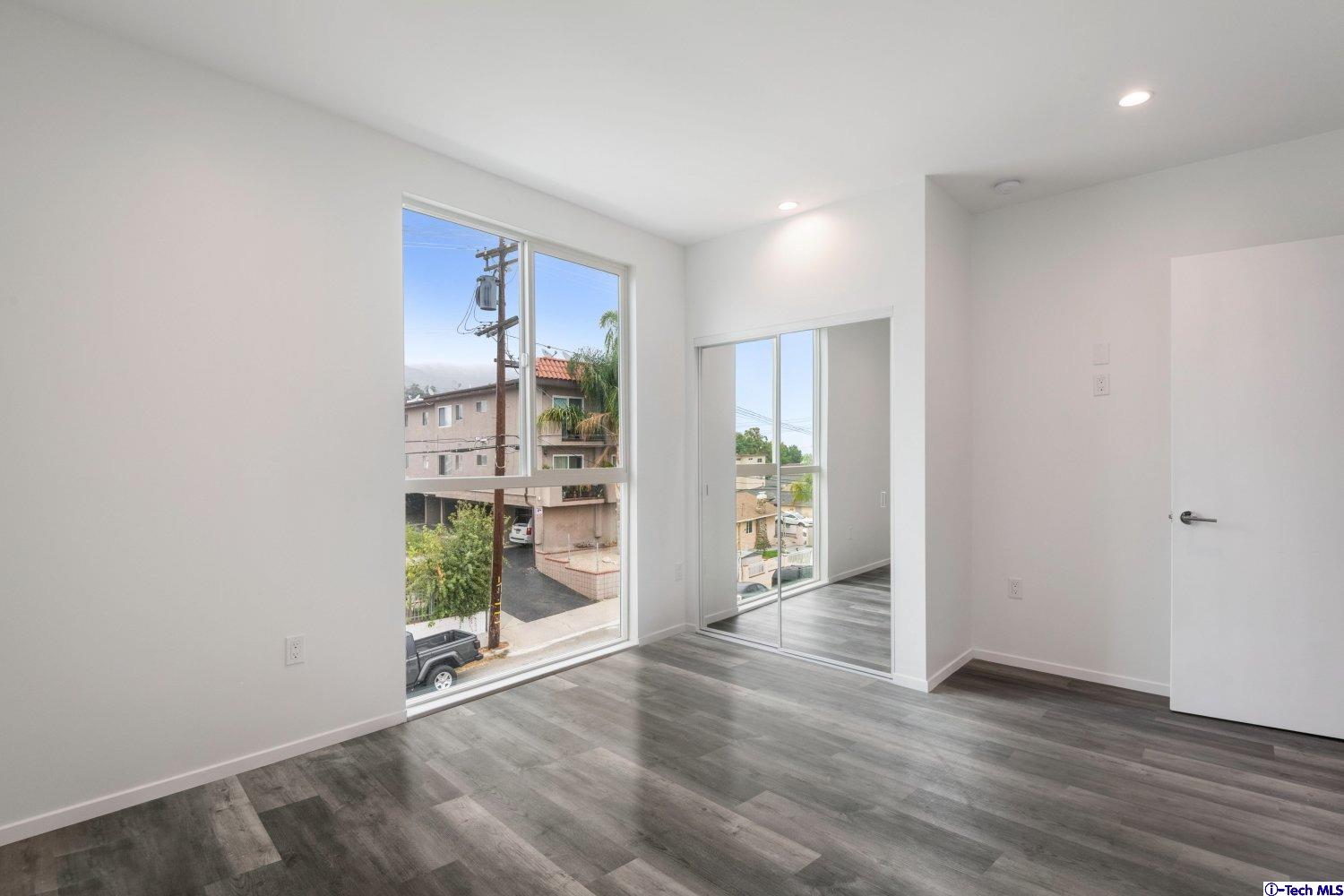 7064 Greeley Street, Unit 202 Tujunga, CA 91042 - Photo 30 of 45 an empty room with floor to ceiling window and wooden floor
