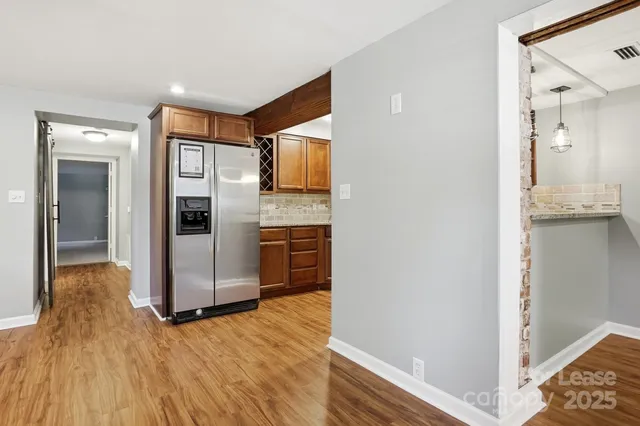 a kitchen with stainless steel appliances granite countertop a refrigerator a stove and a sink with wooden floor