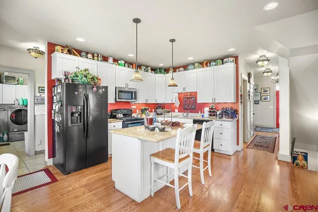 a kitchen with stainless steel appliances a dining table chairs refrigerator and sink