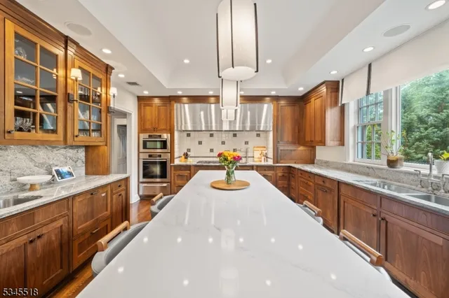 a view of a kitchen with kitchen island granite countertop a large counter top stainless steel appliances and windows