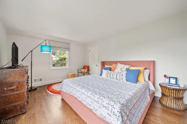 a bedroom with a bed and a flat tv screen on dresser
