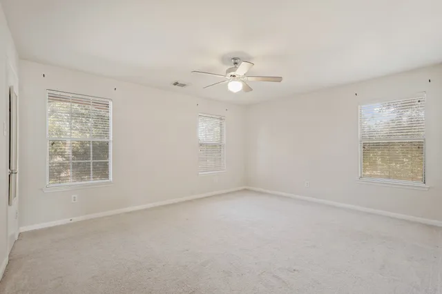an empty room with a window and a fan