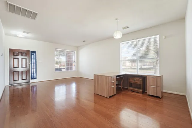 a view of an empty room with a window and wooden floor