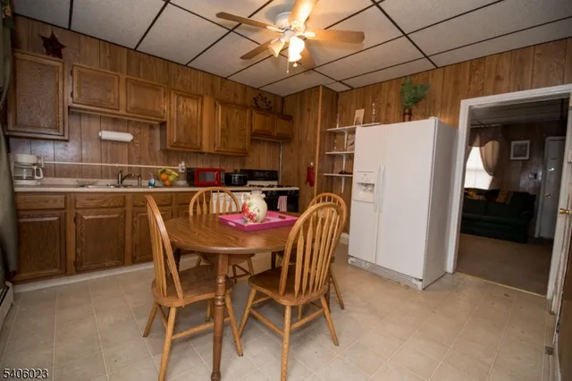 a kitchen with stainless steel appliances a refrigerator a sink dishwasher a dining table and chairs with wooden floor