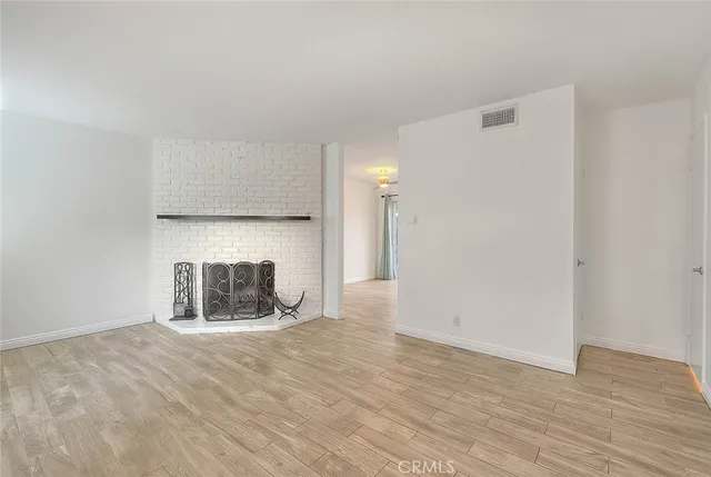 an empty room with wooden floor and fireplace
