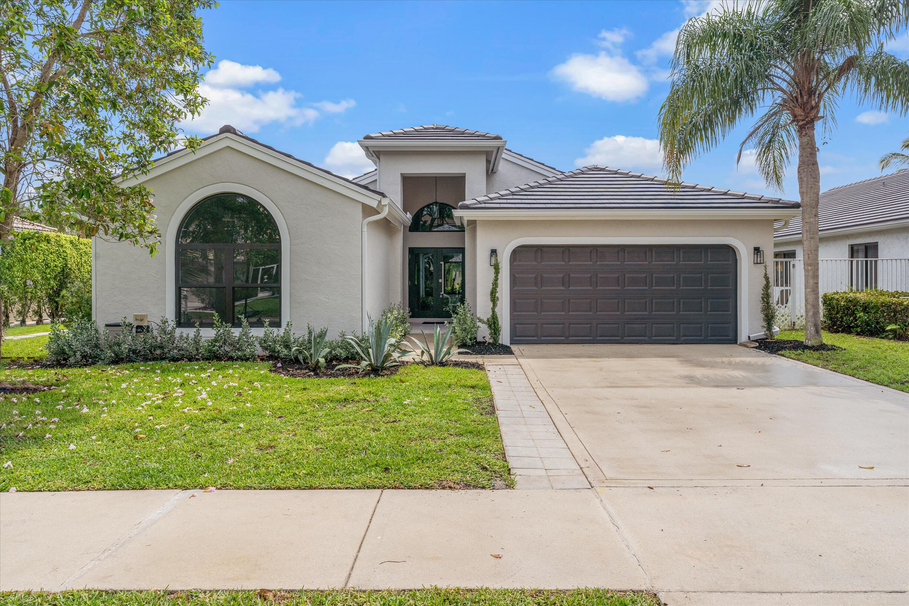 1175 Sea Grape Circle Delray Beach, FL 33445 - Photo 4 of 42 a front view of a house with a garden