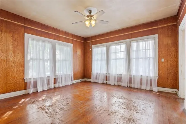 an empty room with windows and ceiling fan