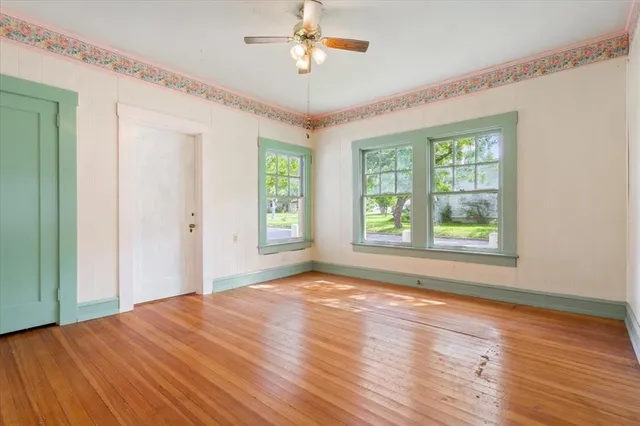 a view of empty room with wooden floor and fan