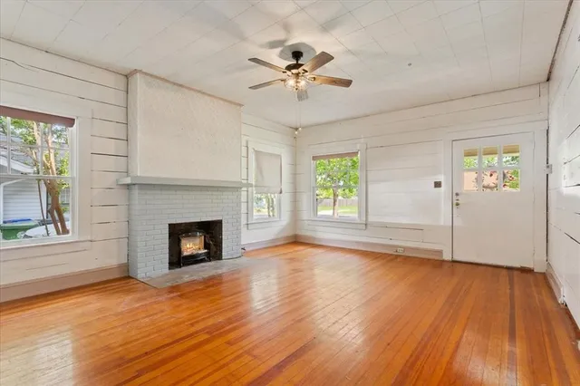 a view of an empty room with wooden floor fireplace and a window