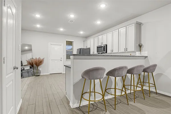 a kitchen with stainless steel appliances granite countertop a stove top oven a refrigerator a dining table and chairs with wooden floor