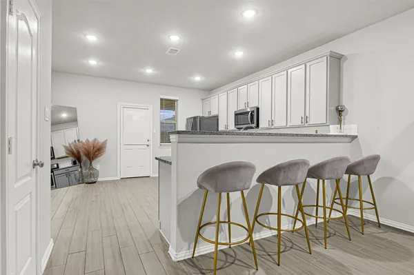 a kitchen with stainless steel appliances granite countertop white cabinets and chairs