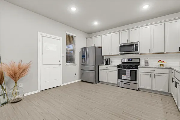 a kitchen with granite countertop white cabinets and stainless steel appliances