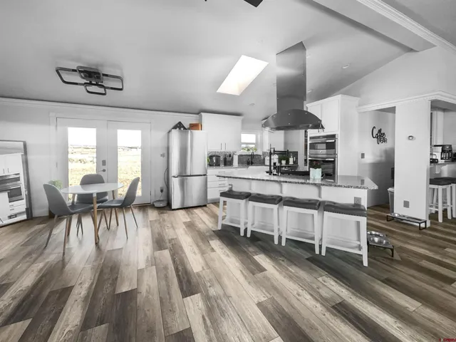 a living room with stainless steel appliances kitchen island granite countertop furniture and a wooden floors