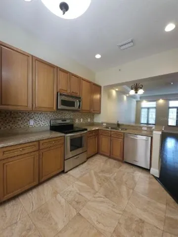 a large kitchen with granite countertop a stove sink and cabinets