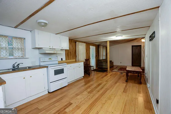 a kitchen with a sink wooden floor and white appliances