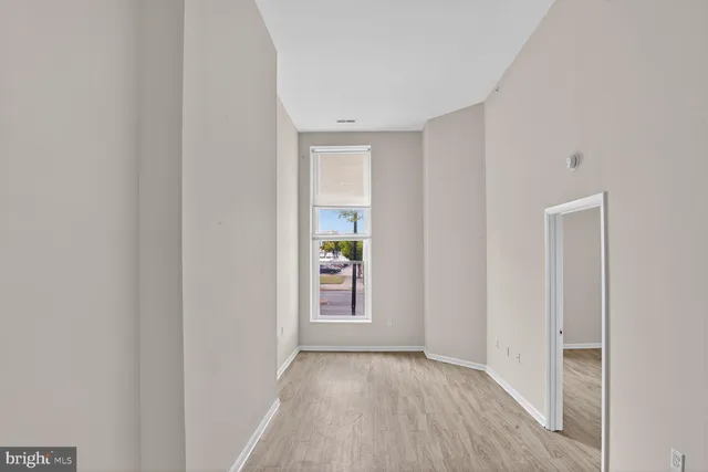a view of an empty room with closet and wooden floor