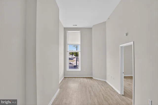 a view of an empty room with closet and wooden floor