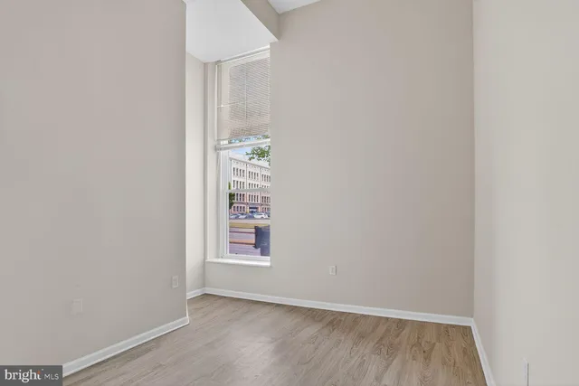 an empty room with wooden floor & closet area