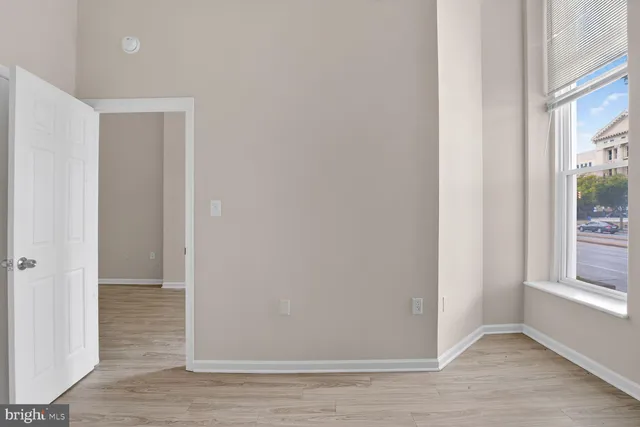 a view of an empty room with closet and wooden floor