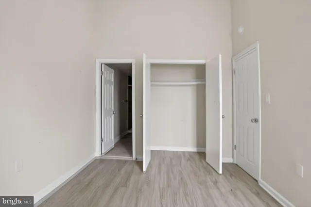 a view of an empty room with wooden floor and closet