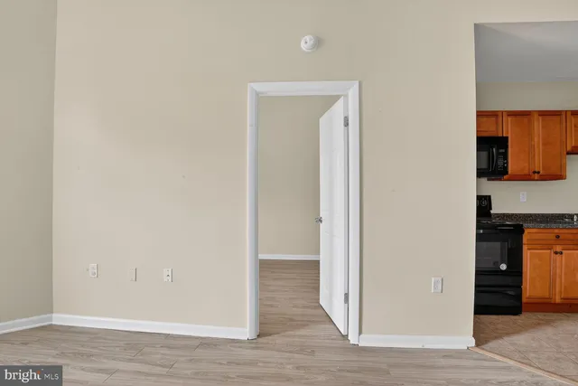 a view of a livingroom with wooden floor and a refrigerator