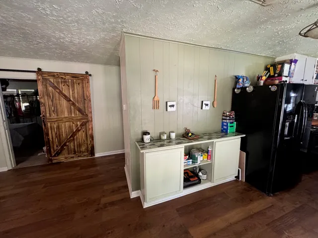 a view of a kitchen with fridge and wooden floor