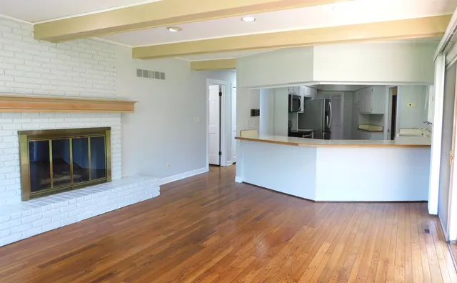 a view of a kitchen with wooden floor and a fireplace